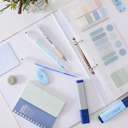  An office desk displaying a notebook, pens, and other stationery items, emphasizing a clean and productive environment.